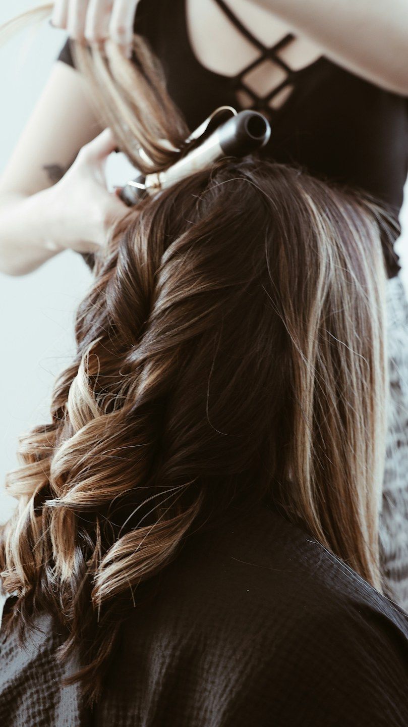 Cabelo castanho iluminado sendo modelado com babyliss