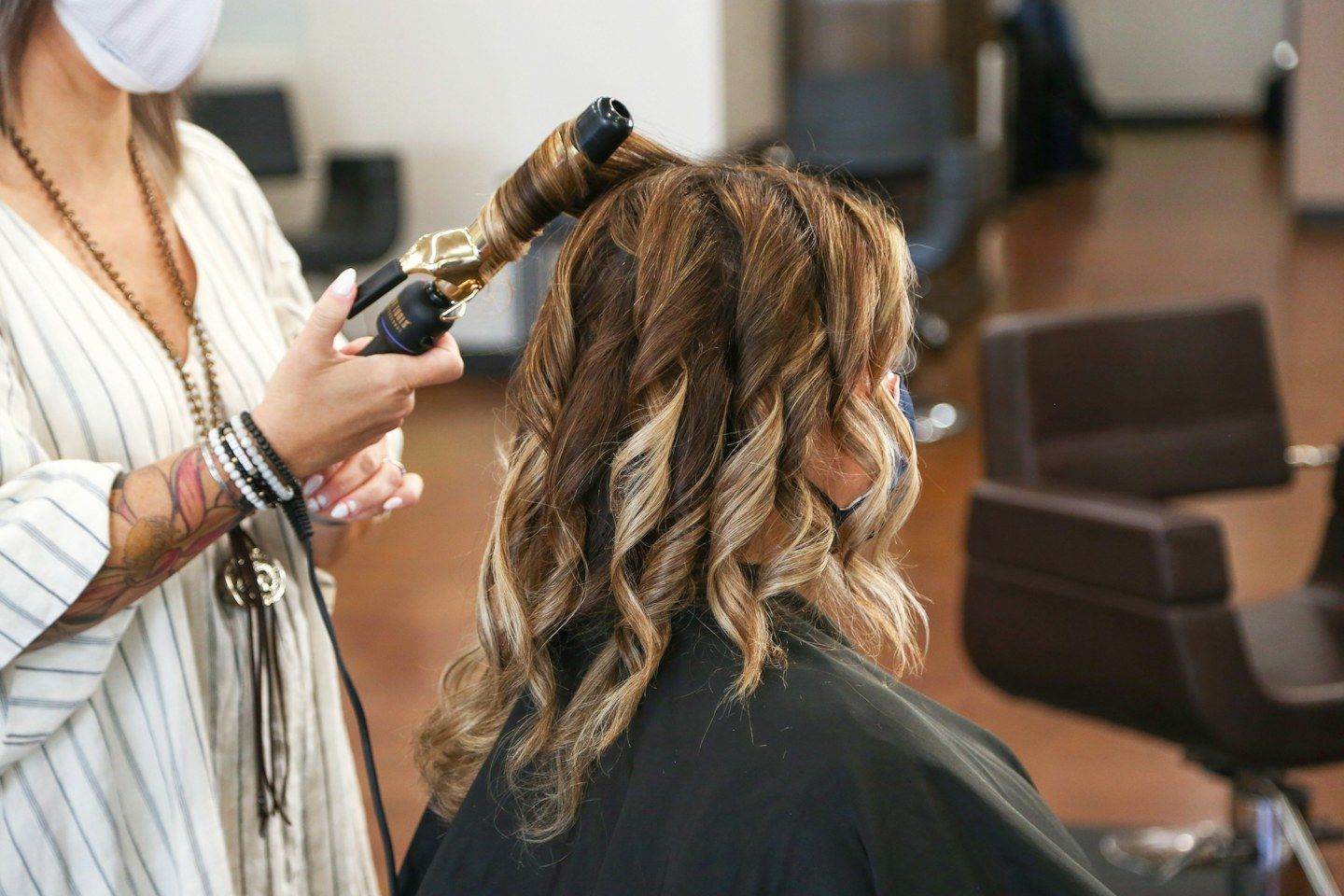 Cabeleireira modelando as mechas de uma cliente com babyliss no salão